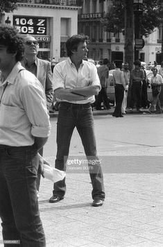 black and white photograph of two men standing in the street, one holding his arms crossed