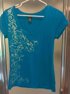 a blue t - shirt with white swirls on it hanging in front of a glass door