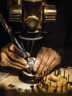 a man is working on a watch in front of a clock and some other tools