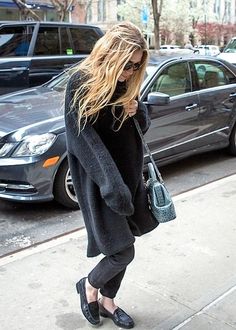 a woman is walking down the sidewalk with her purse