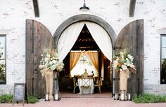 the entrance to a wedding reception is decorated with white flowers and greenery as well as wooden archways