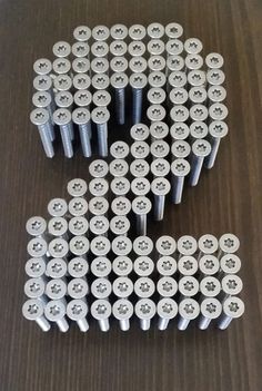 several white screws are arranged in the shape of a number on a brown surface