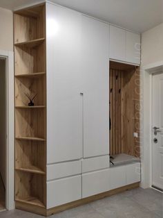 an empty room with white cupboards and shelves on the wall next to a door