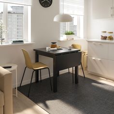 a table with two chairs and a clock on the wall above it in a white room