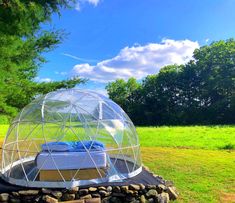 a bed sitting inside of a glass dome in the middle of a field