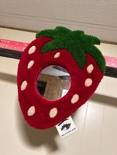 a stuffed strawberry shaped mirror hanging on the wall