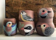 three vases with birds painted on them sitting on a shelf next to a wooden wall