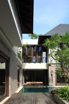 an outdoor swimming pool in front of a house with wooden decking and large windows