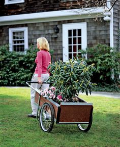 a woman pushing a wheelbarrow with flowers in it