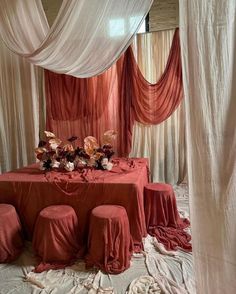 the table is set up with red linens and white draping over it