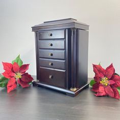 two poinsettias are sitting on a table next to a chest of drawers