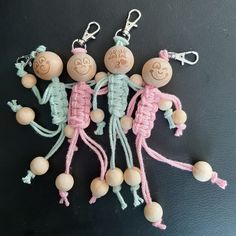 three little wooden dolls are hanging on the wall with their faces drawn in crochet