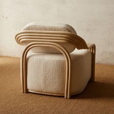 a chair made out of wood and fabric on top of a carpeted floor in front of a white wall