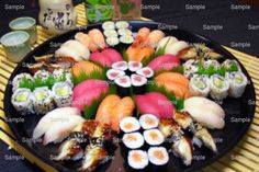 a black plate topped with lots of different types of sushi on top of a table