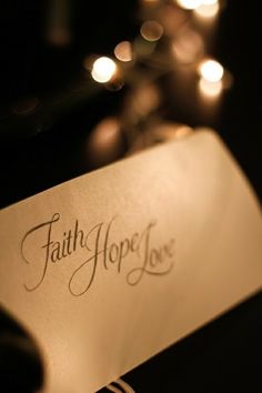 a close up of a paper with the word faith hope on it and some candles in the background