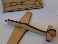 a wooden toy airplane next to a piece of wood that has been carved into it