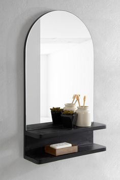 a black shelf with a mirror and bowl on it