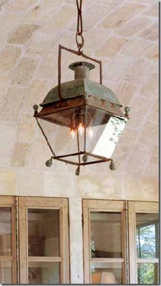 an old fashioned light hanging from the ceiling in a room with stone walls and windows