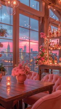 a dining room table with pink chairs and vases filled with flowers in front of large windows