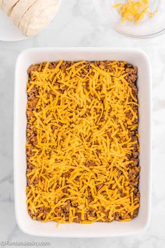 a square casserole dish with cheese and ground beef in it on a marble countertop