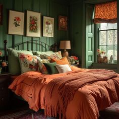 a bedroom with green walls and orange bedspread in front of a window that has pictures on the wall