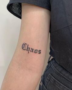 a woman's arm with the word chaos tattooed on her left forearm and an inscription that reads chaos in cursive font