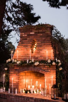 an outdoor fireplace with candles and flowers on it