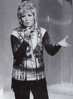 a woman standing in front of a microphone and holding her hand out to the side