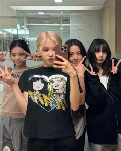 four girls are posing for the camera in front of a mirror with their fingers up