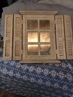 an old wooden window with shutters open on top of a blue and white bed