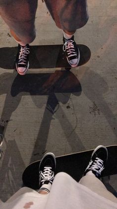 two people standing on skateboards with their feet up