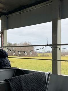 the back of a truck with clothes hanging from it's front end and an open field in the background