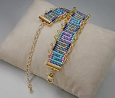 a gold chain bracelet with multicolored seed beads on a beige velvet pillow cover