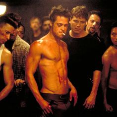 the shirtless man is standing in front of other men with blood all over his body