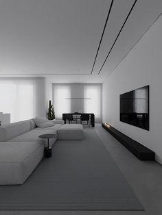 a modern living room with white walls and grey carpeted flooring, large sectional couches in front of a flat screen tv mounted on the wall