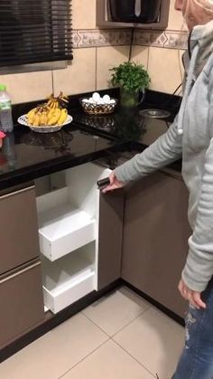 an empty dishwasher in the middle of a kitchen with bananas on the counter