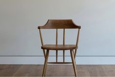 a wooden chair sitting on top of a hard wood floor next to a white wall