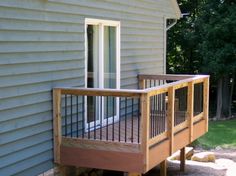 a wooden deck next to a house with a sliding glass door on the front porch