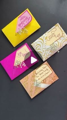 four different colored greeting cards sitting on top of a black table with white and yellow envelopes