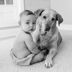 a baby sitting next to a dog on the floor