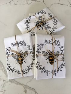 three napkins with bees on them tied up to twine and sitting next to each other