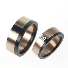 two wedding rings with one diamond in the middle and another on each side, against a white background