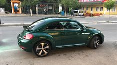 a green car is parked on the side of the road