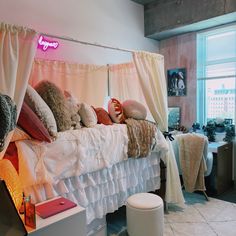 a bed with lots of pillows on top of it in a bedroom next to a window