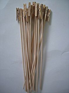 several wooden sticks with clothes pins attached to them on a white surface, lined up against each other