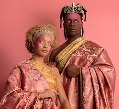 two people dressed in pink and gold standing next to each other on a pink background