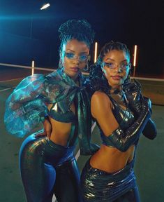 two women dressed in shiny clothing posing for the camera with their arms around each other