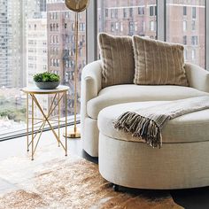 a living room filled with furniture and a large window covered in lots of tall buildings