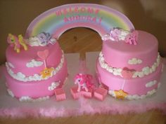 there is a pink cake with pony decorations on the top and rainbow in the background