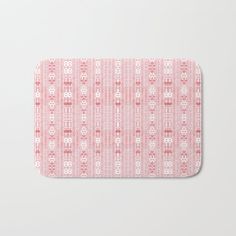 a pink and white bath mat with an ornate pattern on it, in front of a white background